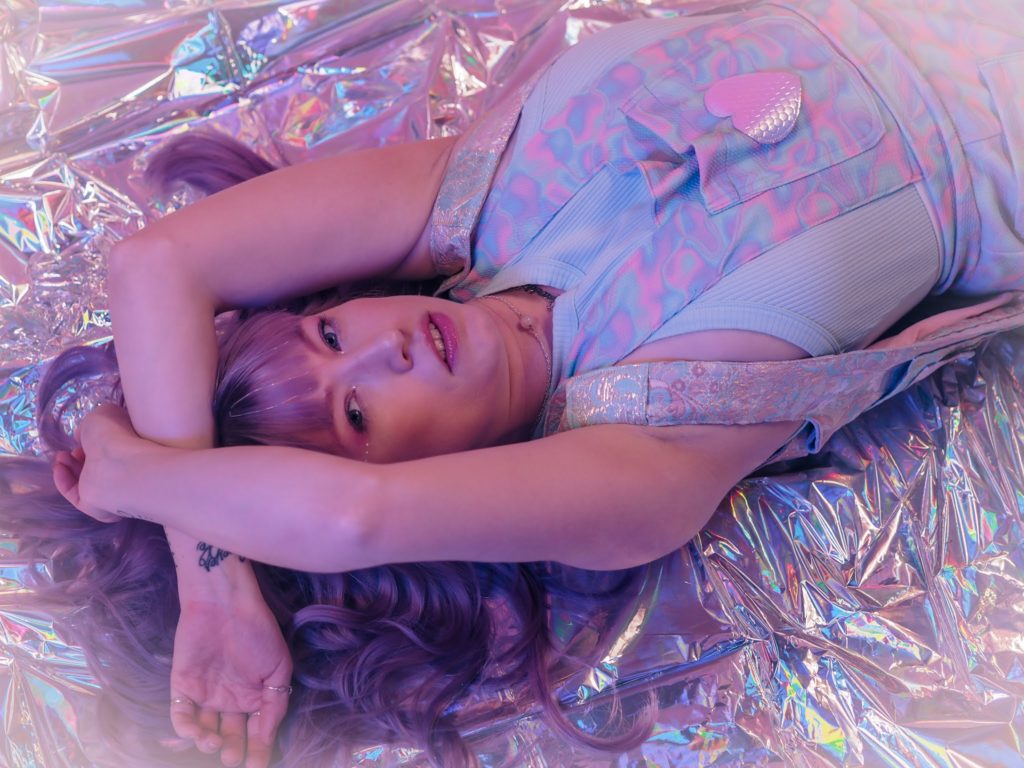 Color photo of Verronica Kirei laying on holographic floor
