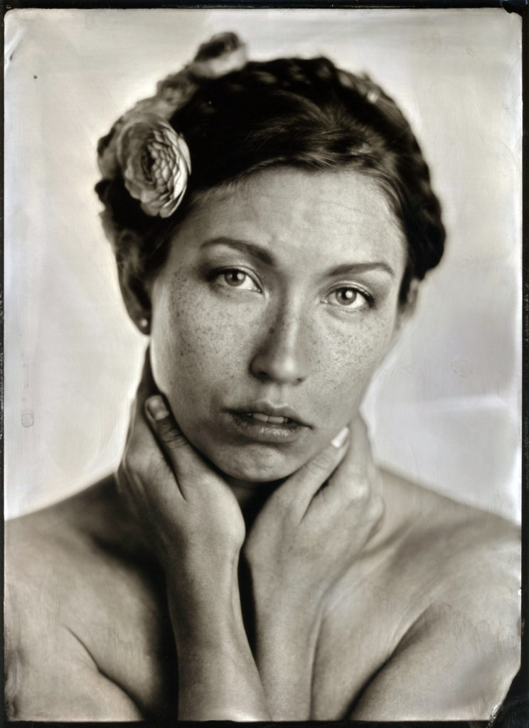 Black and white tintype photo of Verronica Kirei facing the camera with flowers in hair.