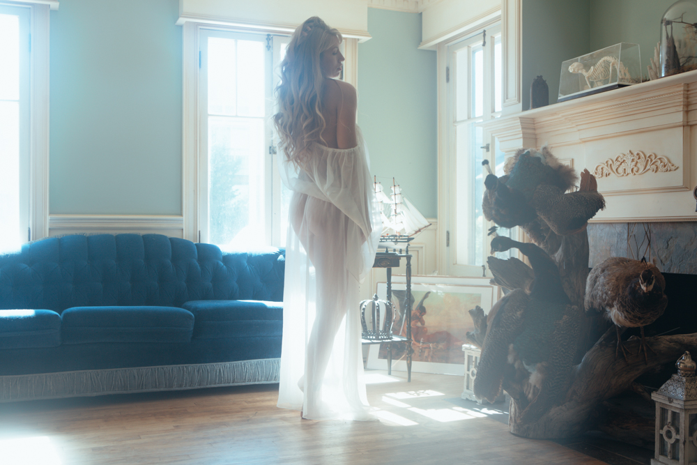 Color photo of Verronica Kirei in living room wearing sheer white gown.